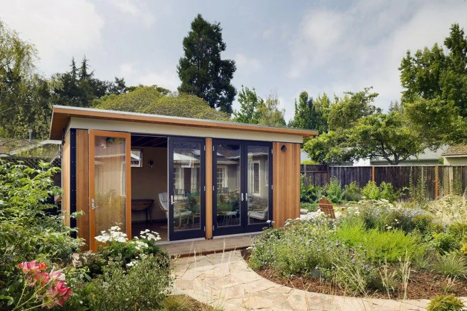 Une cabane de jardin aménagé tendance avec des portes vitrées. 