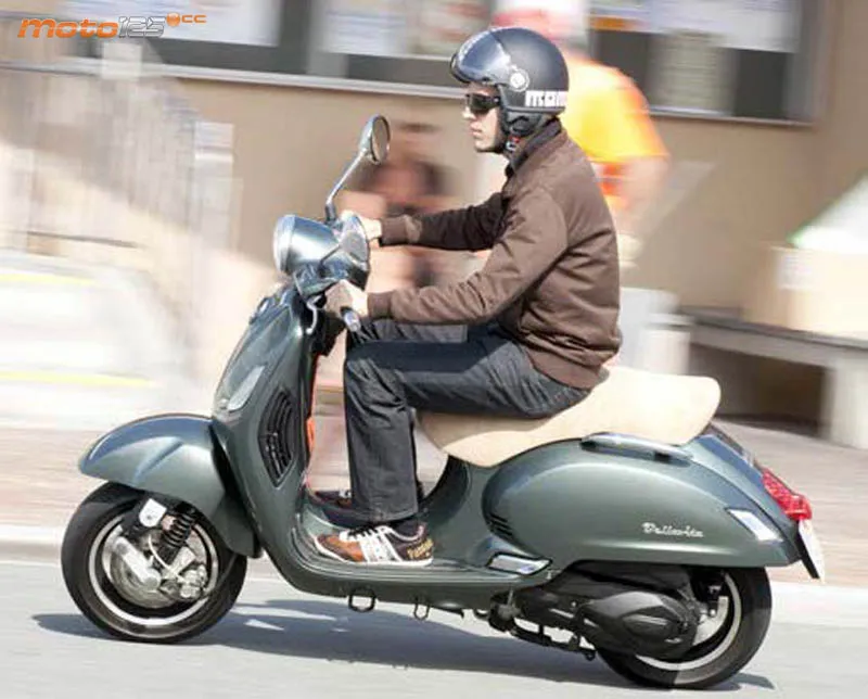 Un homme portant un casque sur un scooter gris