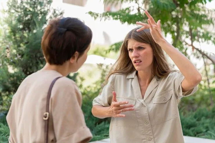 Deux femmes qui se disputent. L'une d'elle fait des gestes avec les mains.