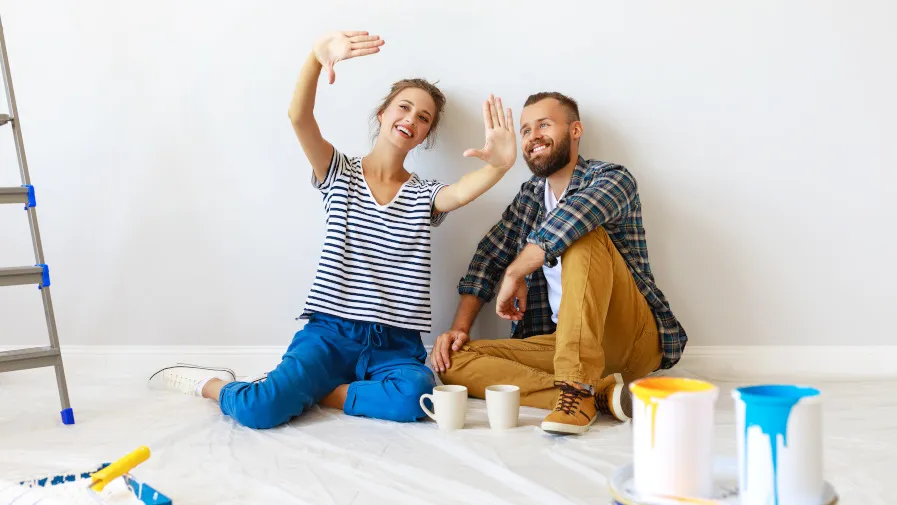 Une femme et un homme faisant assis par terre en attendant de peindre leur mur. 