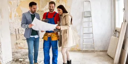 Un couple en train de discuter avec un artisan en tenant un papier dans les mains.