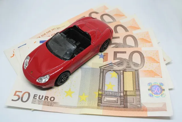 Une petite voiture rouge posée sur quelques billets de 50 euros. 