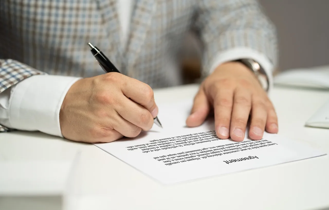 Un homme en train de signé un document. 