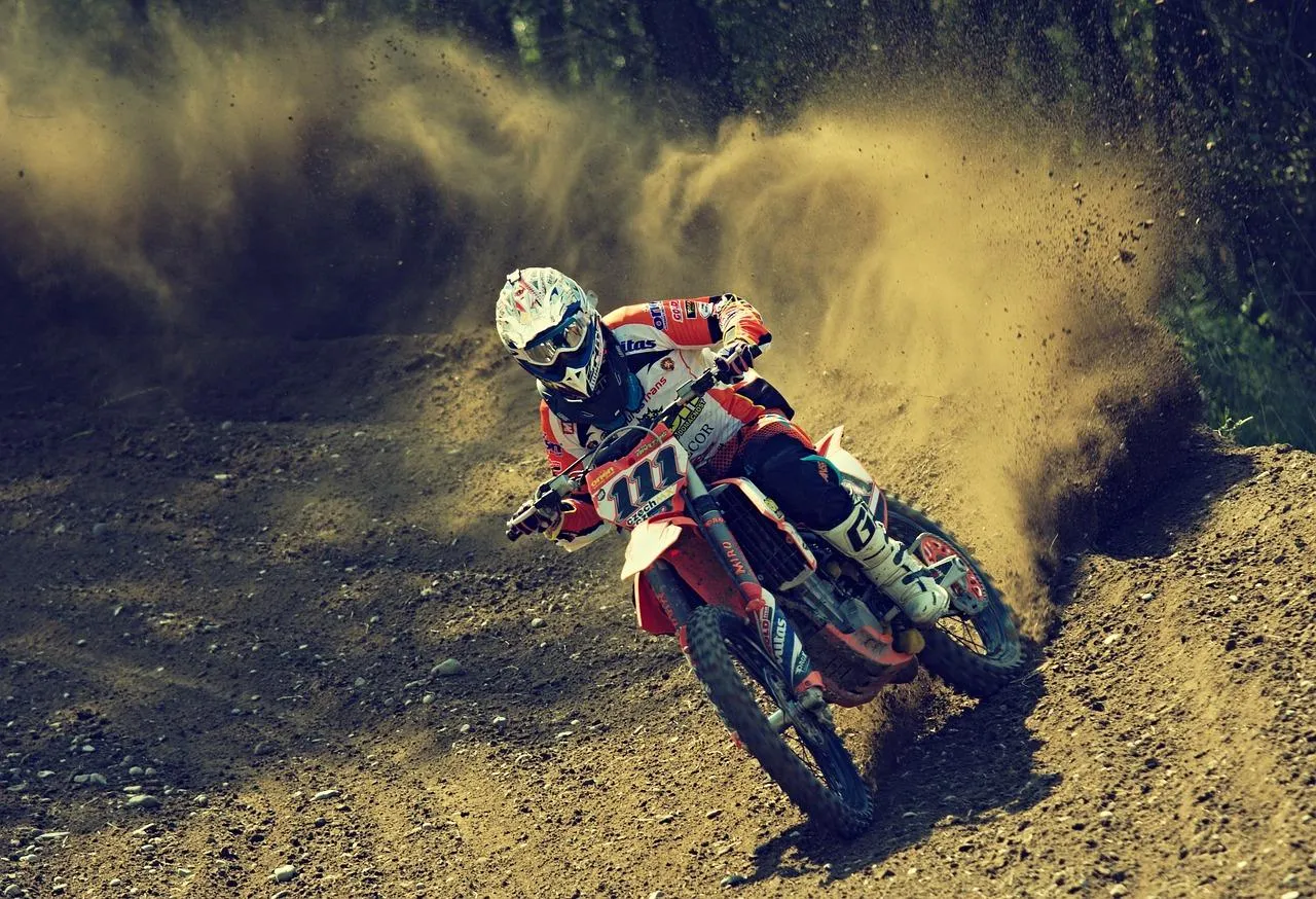 Un pilote de moto-cross en pleine course sur une route de terre.