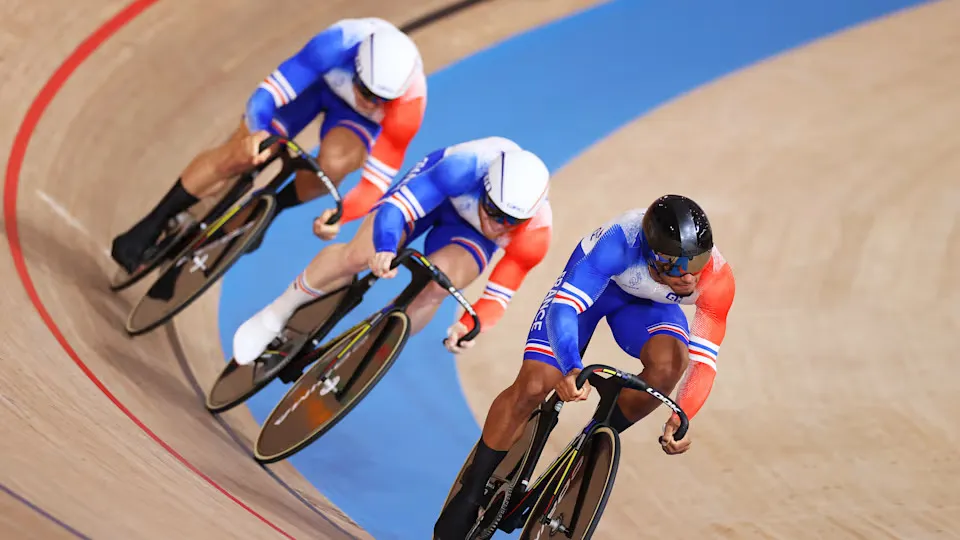 3 cyclistes en plein effort sur une piste de course.