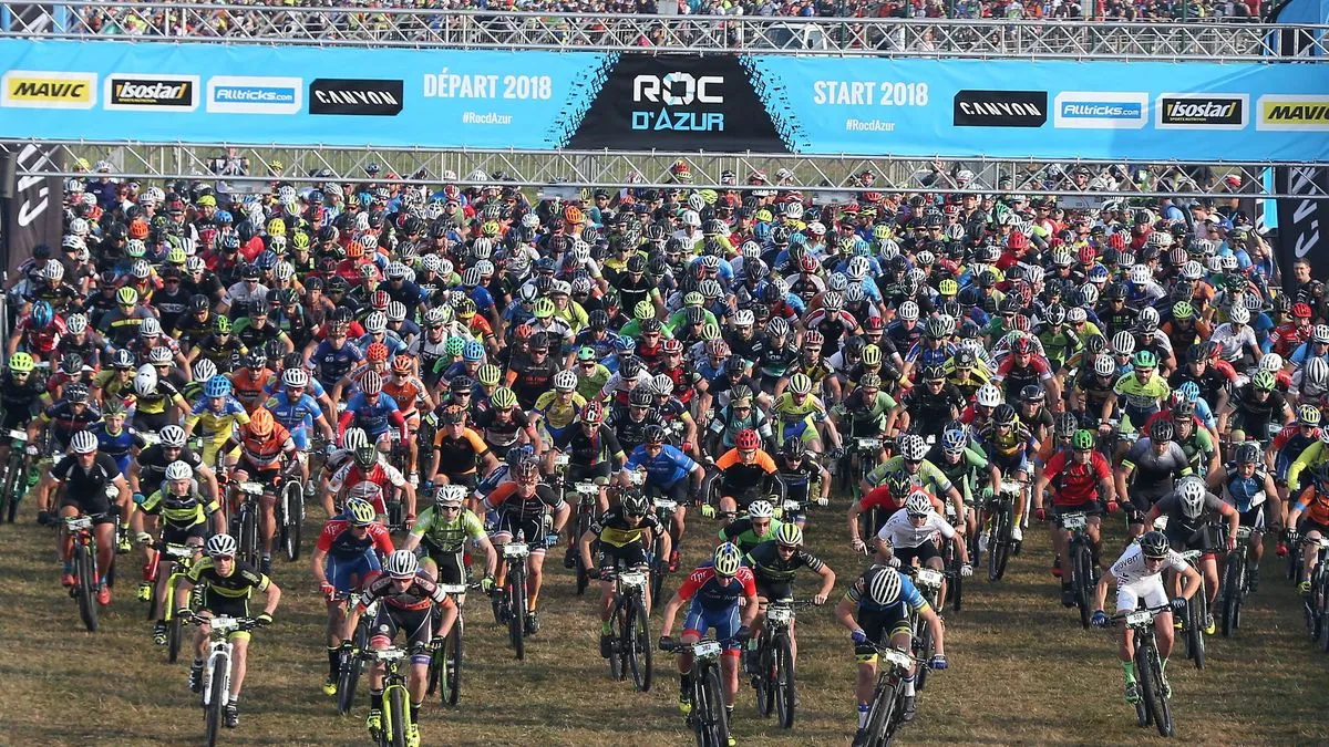 Une photo du départ du Roc d’Azur de 2023 avec tous les participants en maillot à bord de leur VTT.