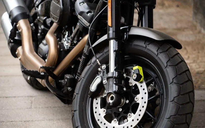 Une moto garée dans la rue avec un zoom sur la gente.