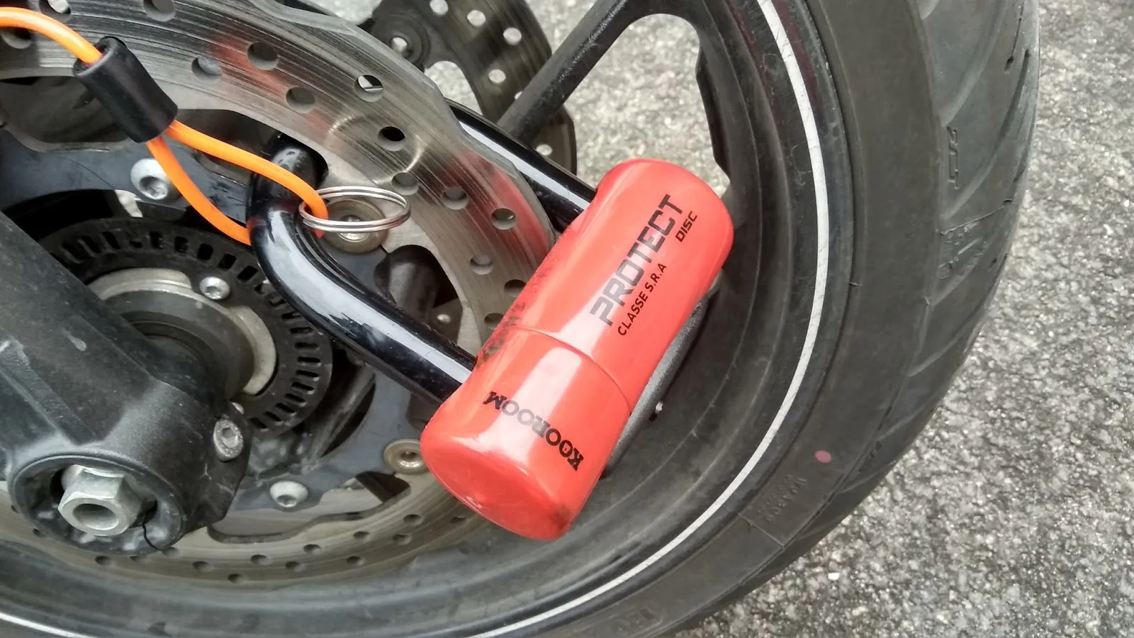 Un Antivol KOOROOM Protect Chain et Bloque Disque SRA sur un pneu de scooter.