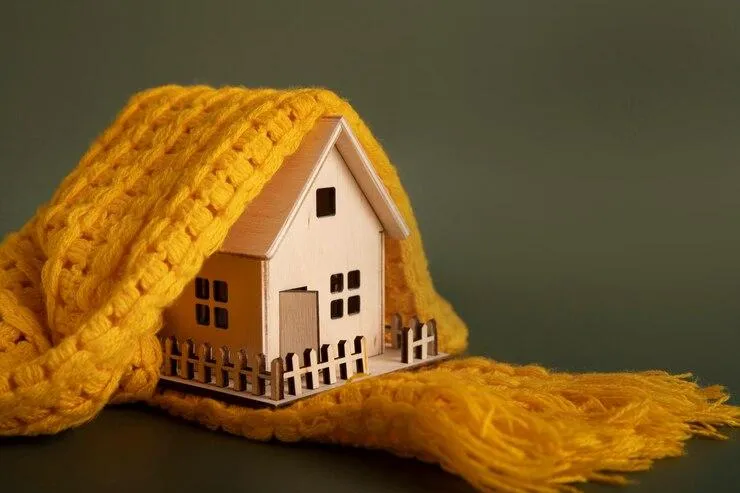Une maquette de maison en bois entourée d'un foulard jaune