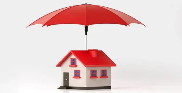 Une maquette de maison avec un toit rouge sous un parapluie rouge
