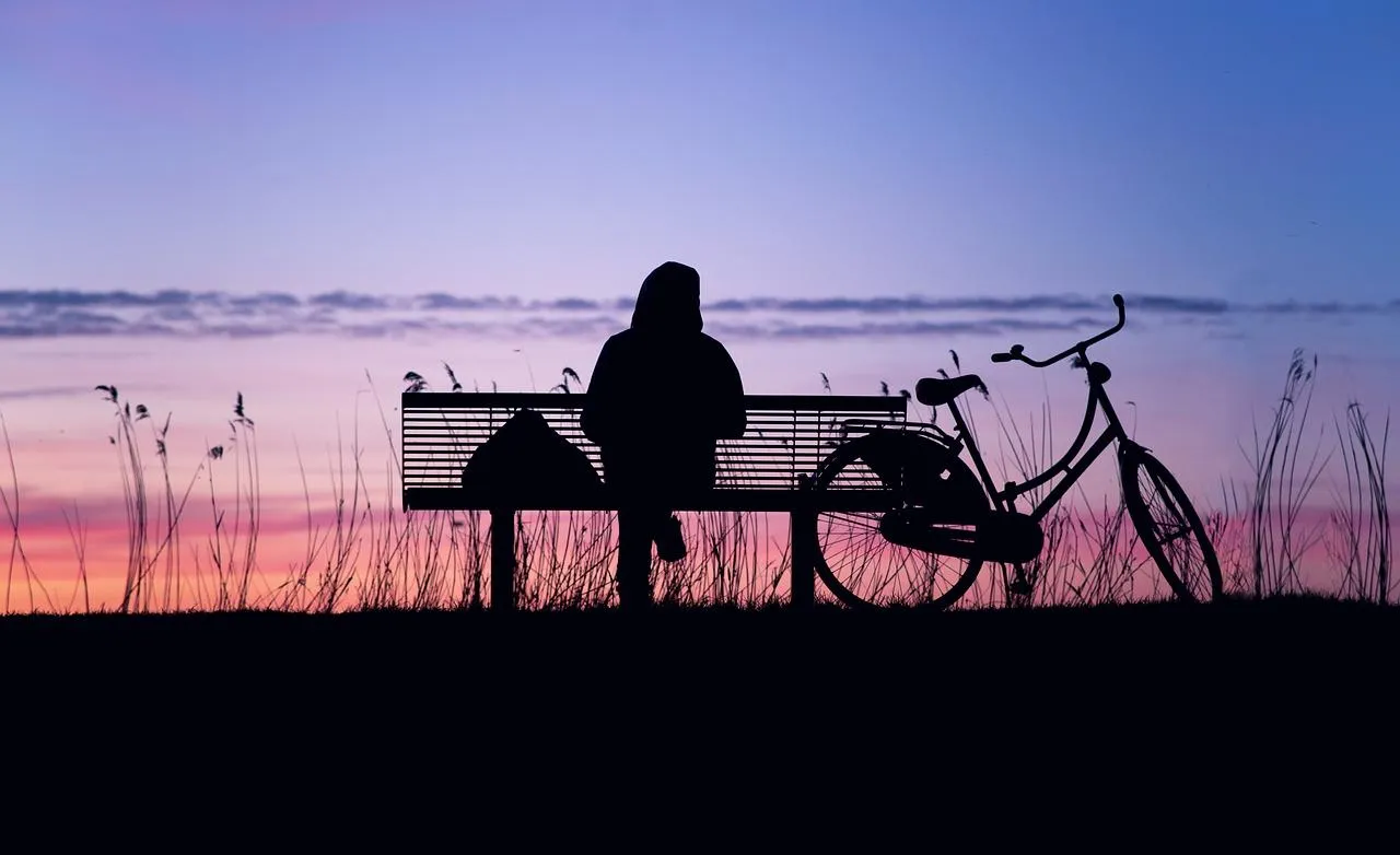 Une personne qui s'assoit sur un banc à côté d'un vélo