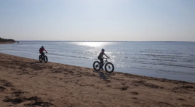 Un enfant et un homme qui roule sur la plage avec leur fatbike