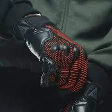 Un homme qui enfile les gants Dainese Unruly Ergo-Tek rouge et noir