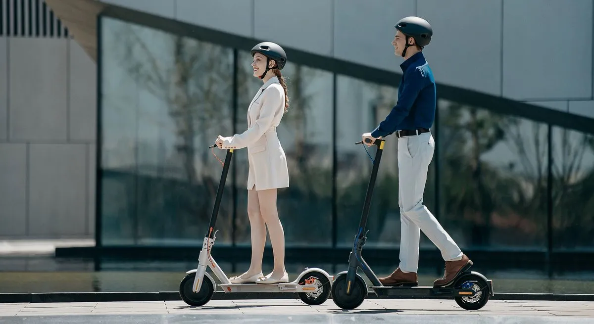 Un couple qui conduit les différents modèles de trottinette électrique Xiaomi Mi scooter 3 dans la rue.
