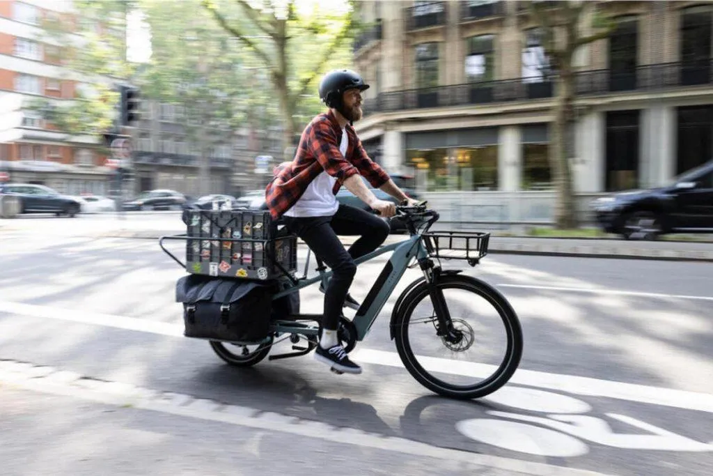 Un homme qui conduit un vélo électrique longtail dans la rue.