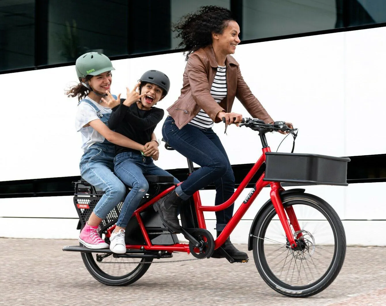 Une femme qui conduit ses enfants à bord d'un vélo électrique longtail.