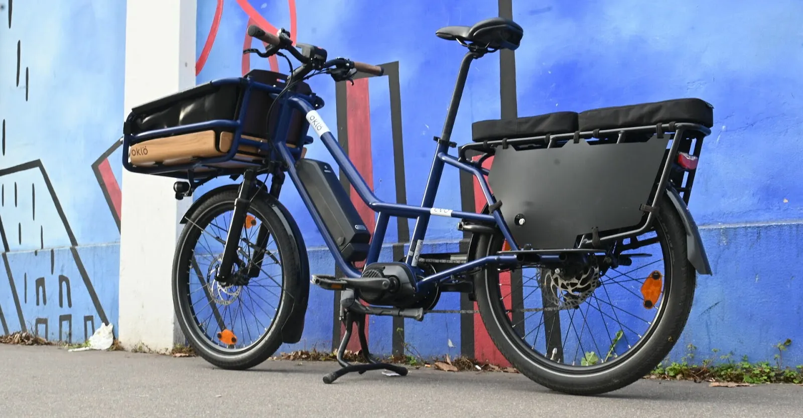 Un vélo longtail bleu garé devant un mur bleu.