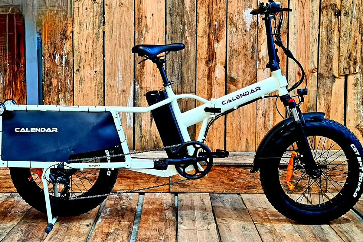 Un vélo longtail blanc garé devant un mur en bois