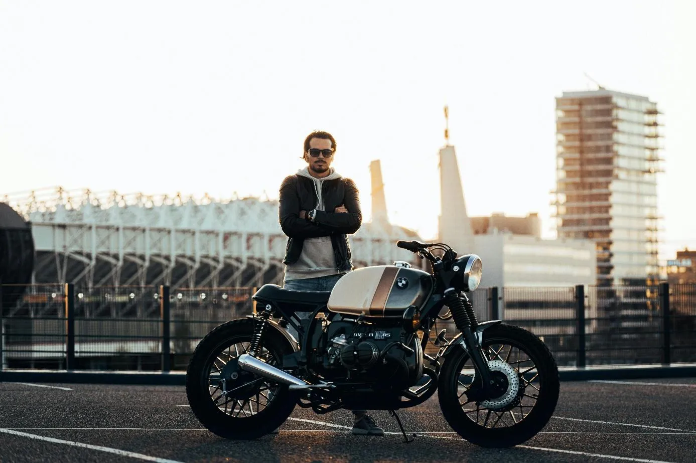 Un homme qui se tient debout derrière sa moto garée sur un parking.