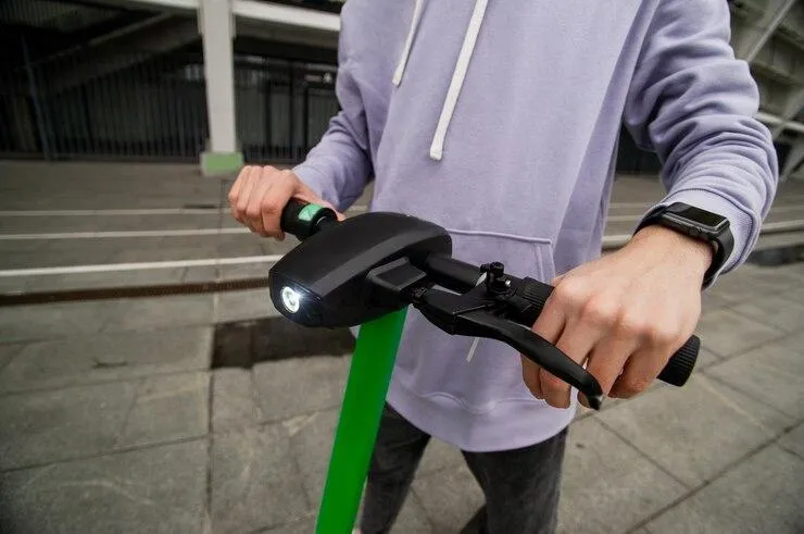 Un homme qui tient le guidon d'une trottinette électrique avec une lumière LED