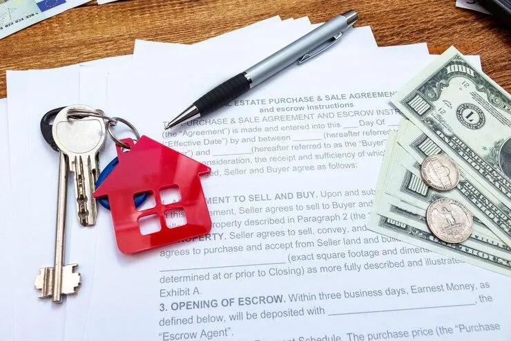 Des clés posées sur des documents à côté d'un stylo et quelques billets