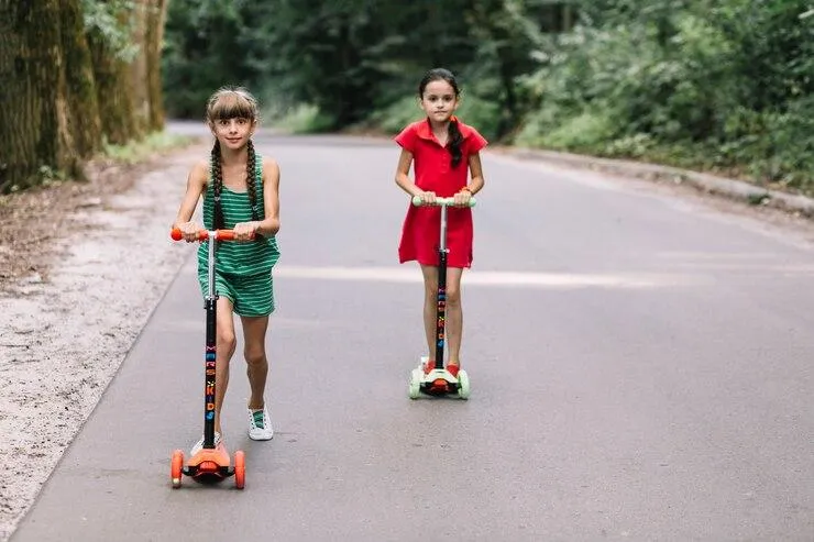 Deux petites filles qui roulent sur leur trottinette électrique sur une route