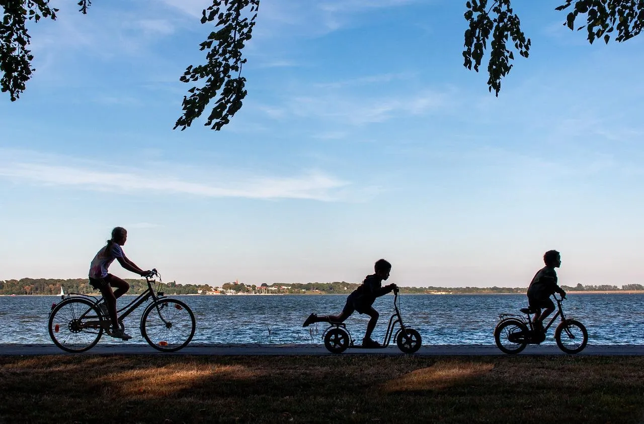 3 enfants qui se baladent à vélo au bord de l'eau.