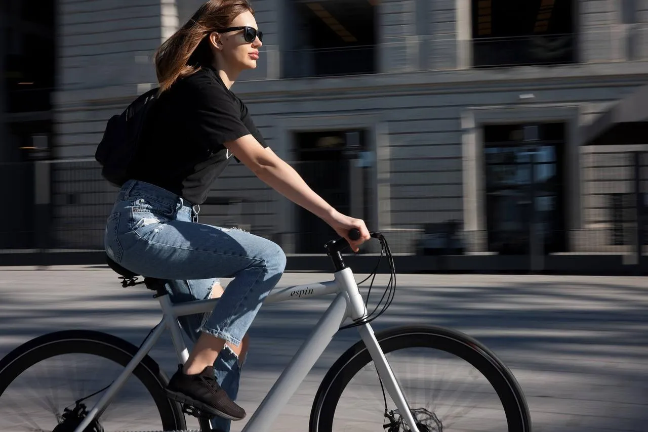 Une femme qui roule à bord d'un vélo électrique blanc.