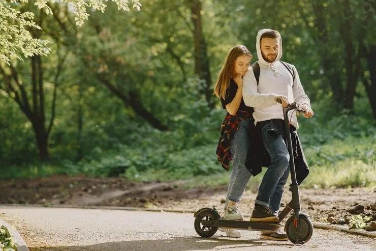 Un couple qui tente de rouler sur une seuple trottinette
