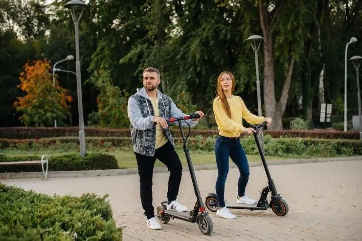 Un couple qui roule sur deux trottinettes dans la rue
