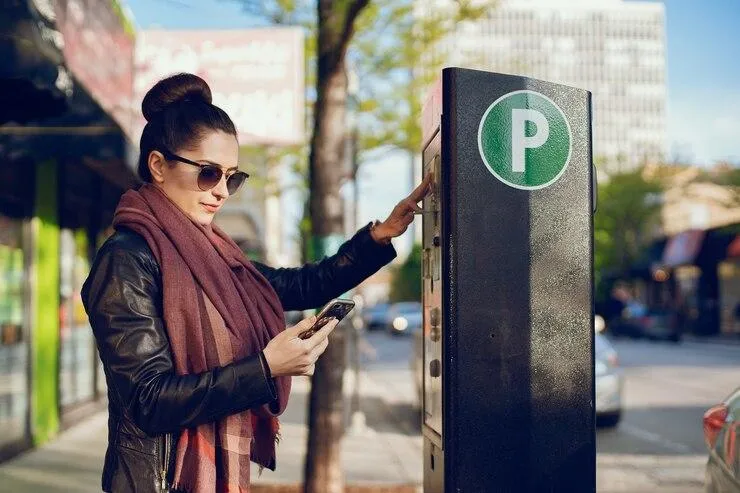 Une femme qui paie sur une borne un emplacement de parking via son Smartphone