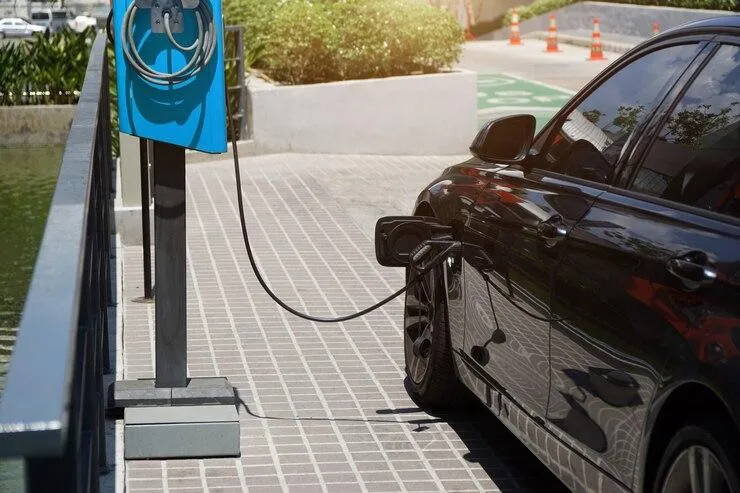 Une voiture garée sur un emplacement et qui est branchée sur une borne de recharge électrique