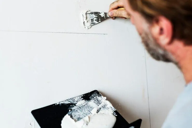 Un homme qui bouche une fissure sur un mur