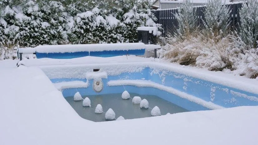 Une piscine presque vide entourée de neige