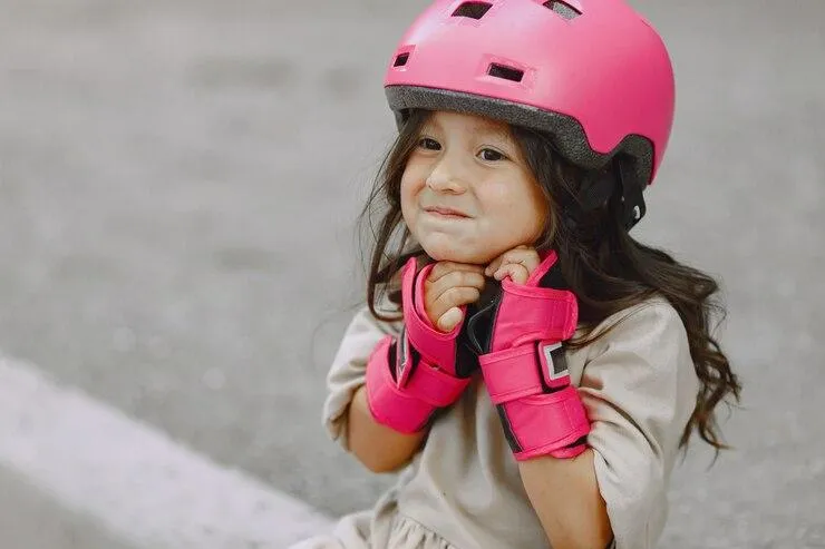 Une petite fille qui enfile un casque rose