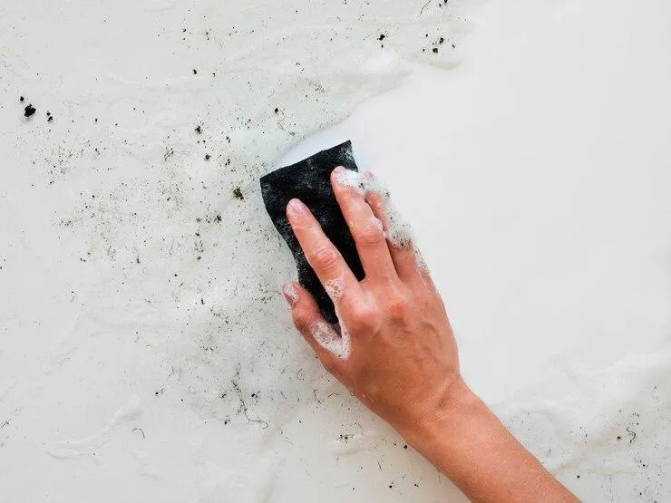 Une personne avec une éponge qui nettoie un mur