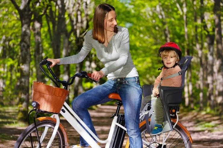 Une femme qui conduit son fils sur un siège enfant à l'arrière d'un vélo