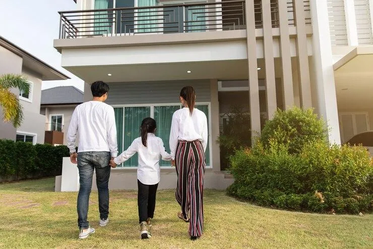 Une famille avec un homme, une femme et une petite fille qui entre dans une maison