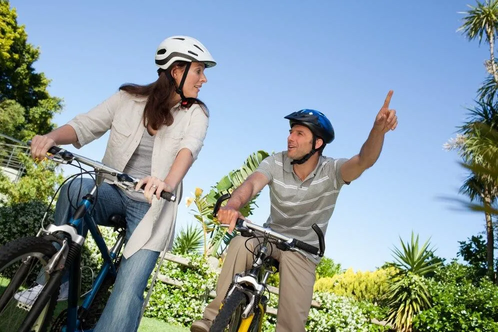 Un homme qui montre une direction à une femme. Tous les deux sont sur des vélos
