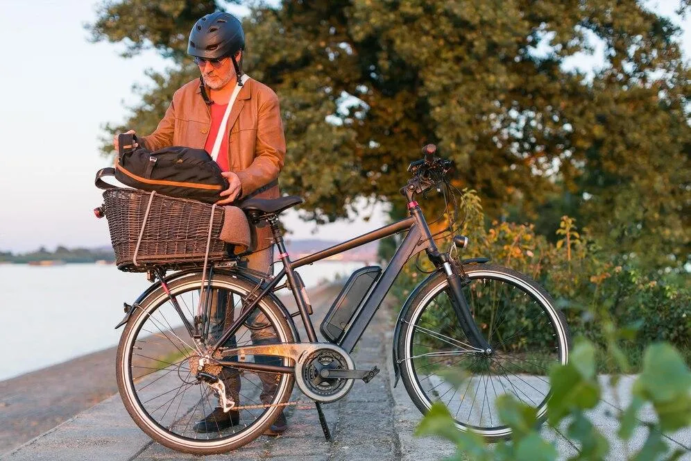 Un homme qui pose un sac à dos sur le panier arrière d'un vélo à l'arrêt