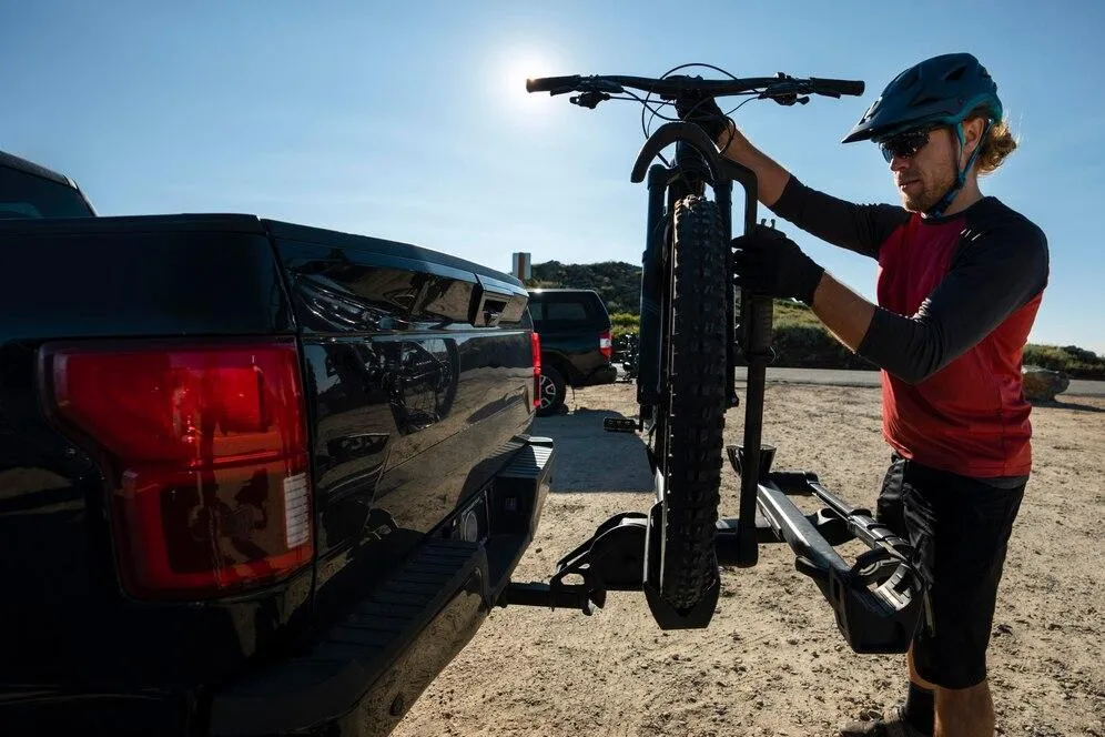 Un homme qui charge un vélo sur une remorque arrière installée sur une voiture
