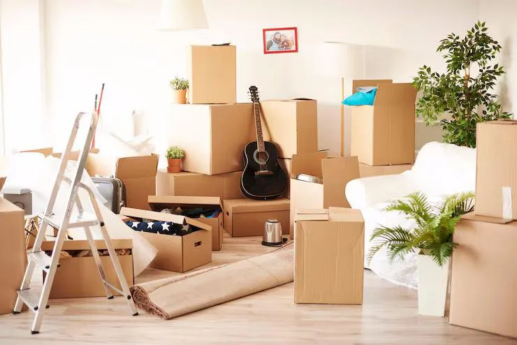 Des cartons posés dans une pièce avec une guitare et un escalier