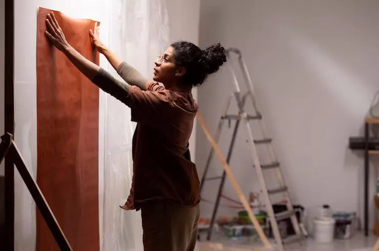 Une femme qui essai un papier peint sur un mur