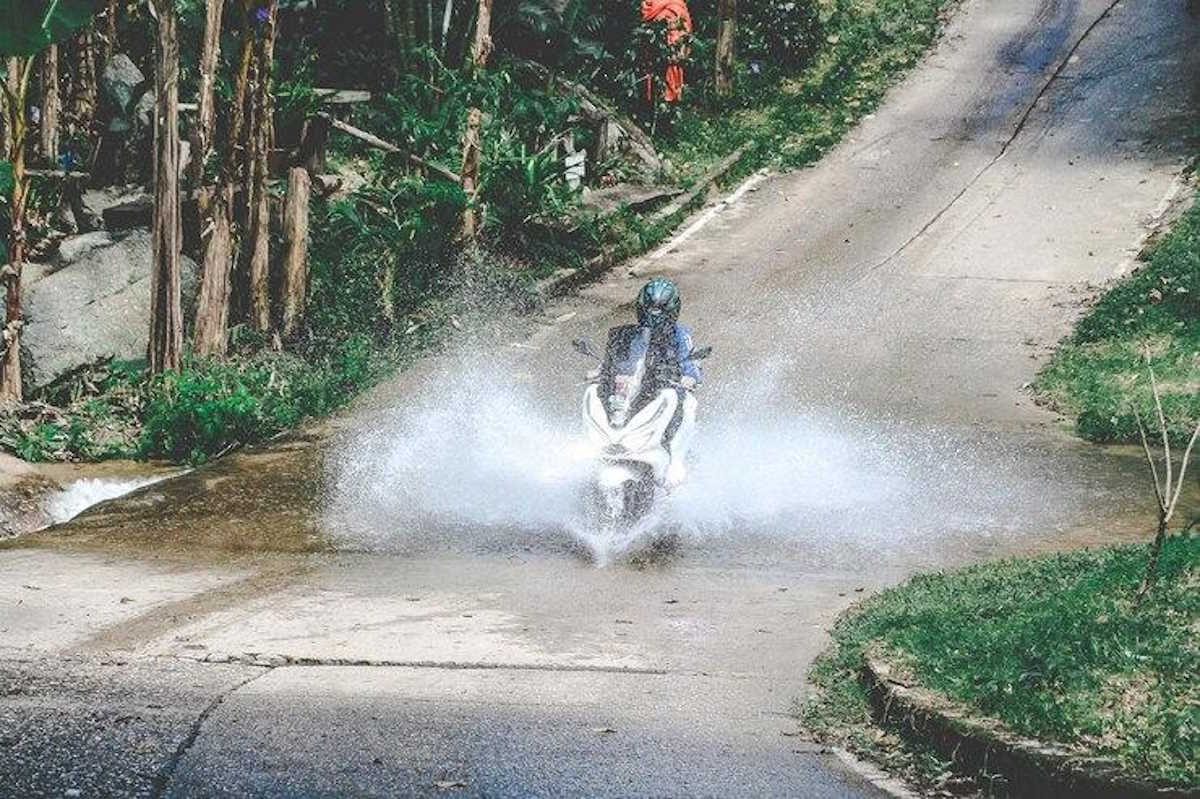 Une personne sur un scooter électrique qui roule dans une grosse flaque d'eau
