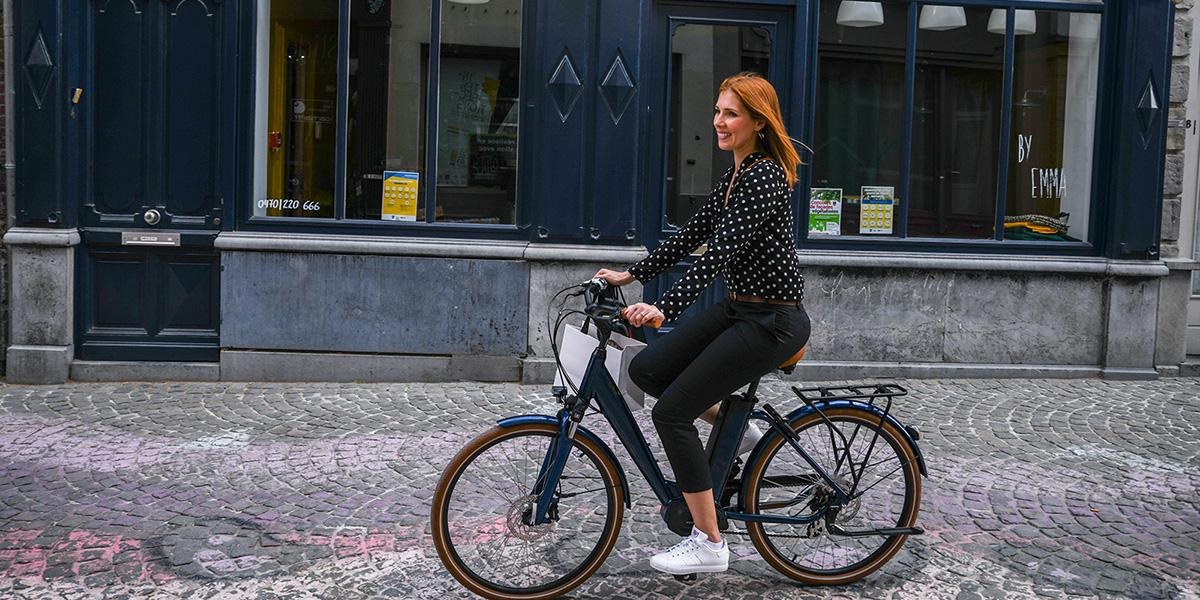 Une femme qui roule sur un vélo O2Feel Ivog 4 sur une route en pavé