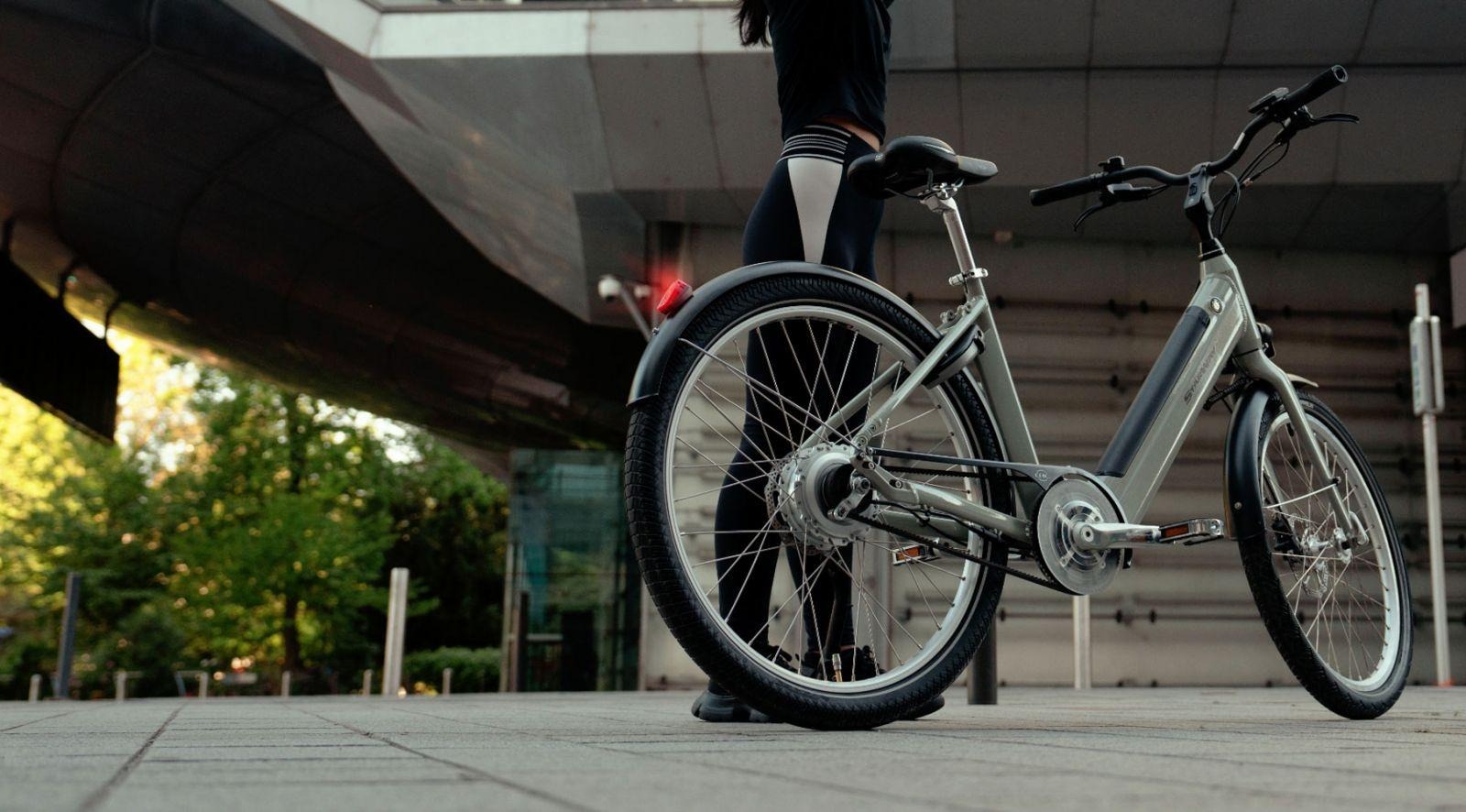 Une femme debout à côté du vélo Starway Révélation