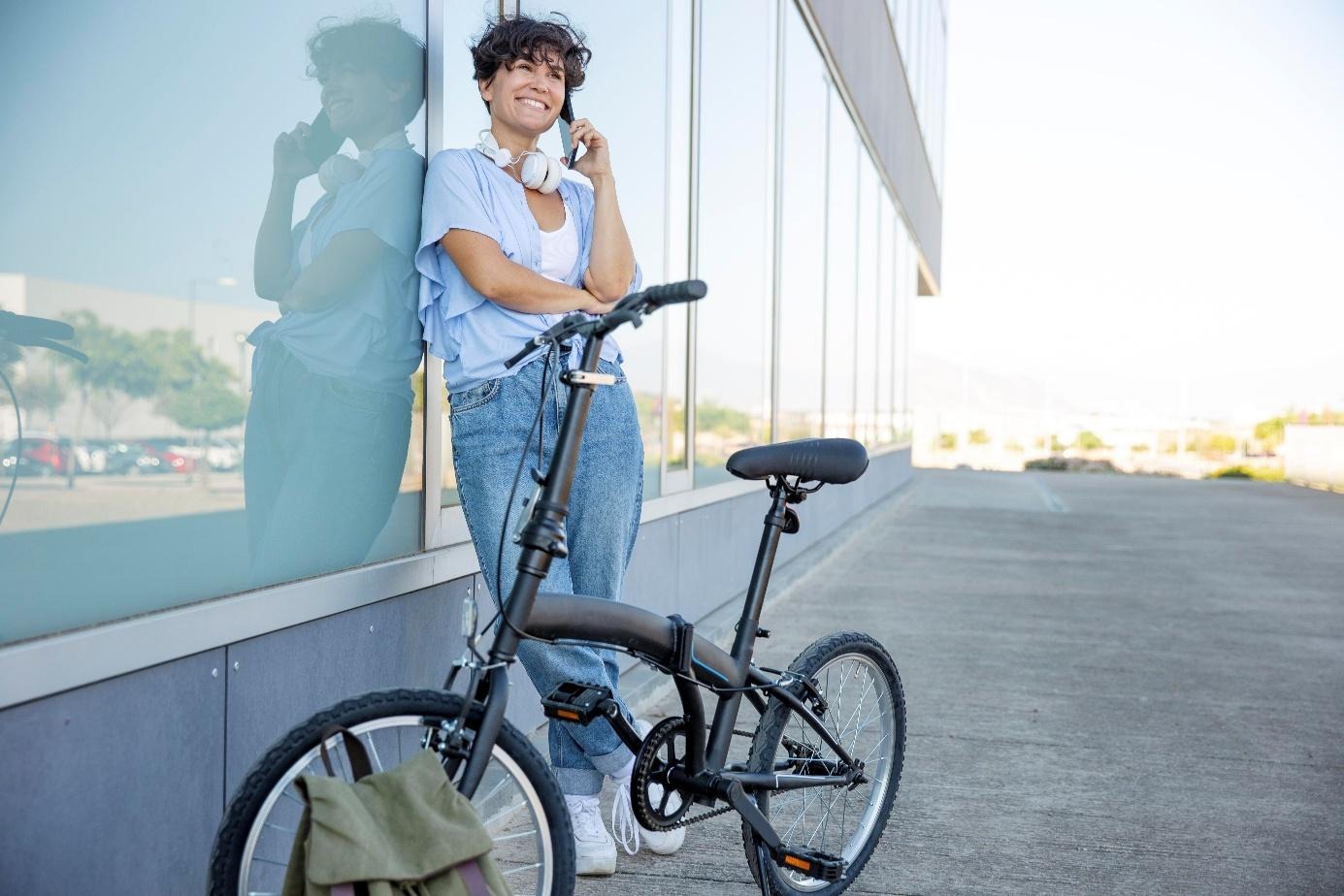 Une femme qui téléphone debout à côté d'un vélo électrique pliant