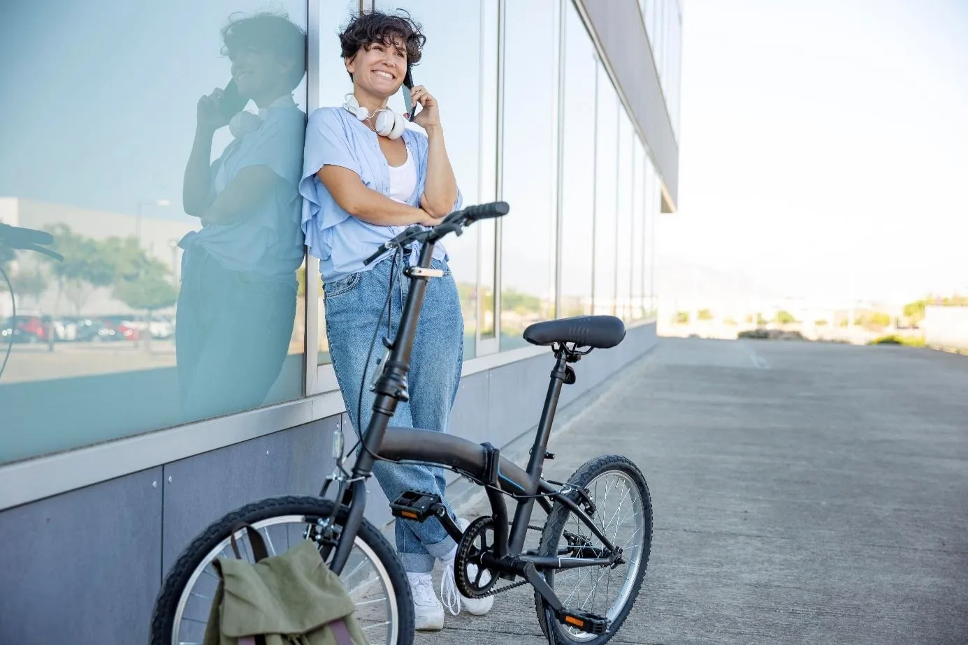 Une femme qui téléphone debout à côté d'un vélo électrique pliant