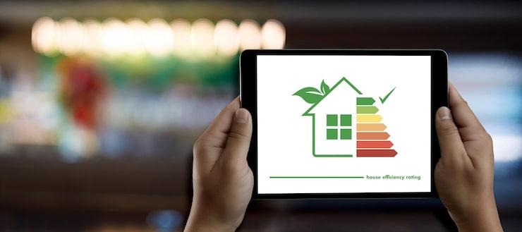 Une personne qui tient une tablette avec le logo des notes énergétiques d'une maison