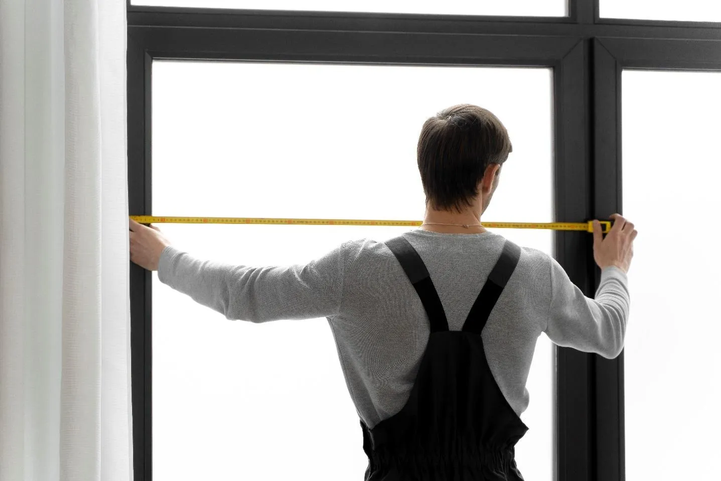 Un homme qui mesure une fenêtre